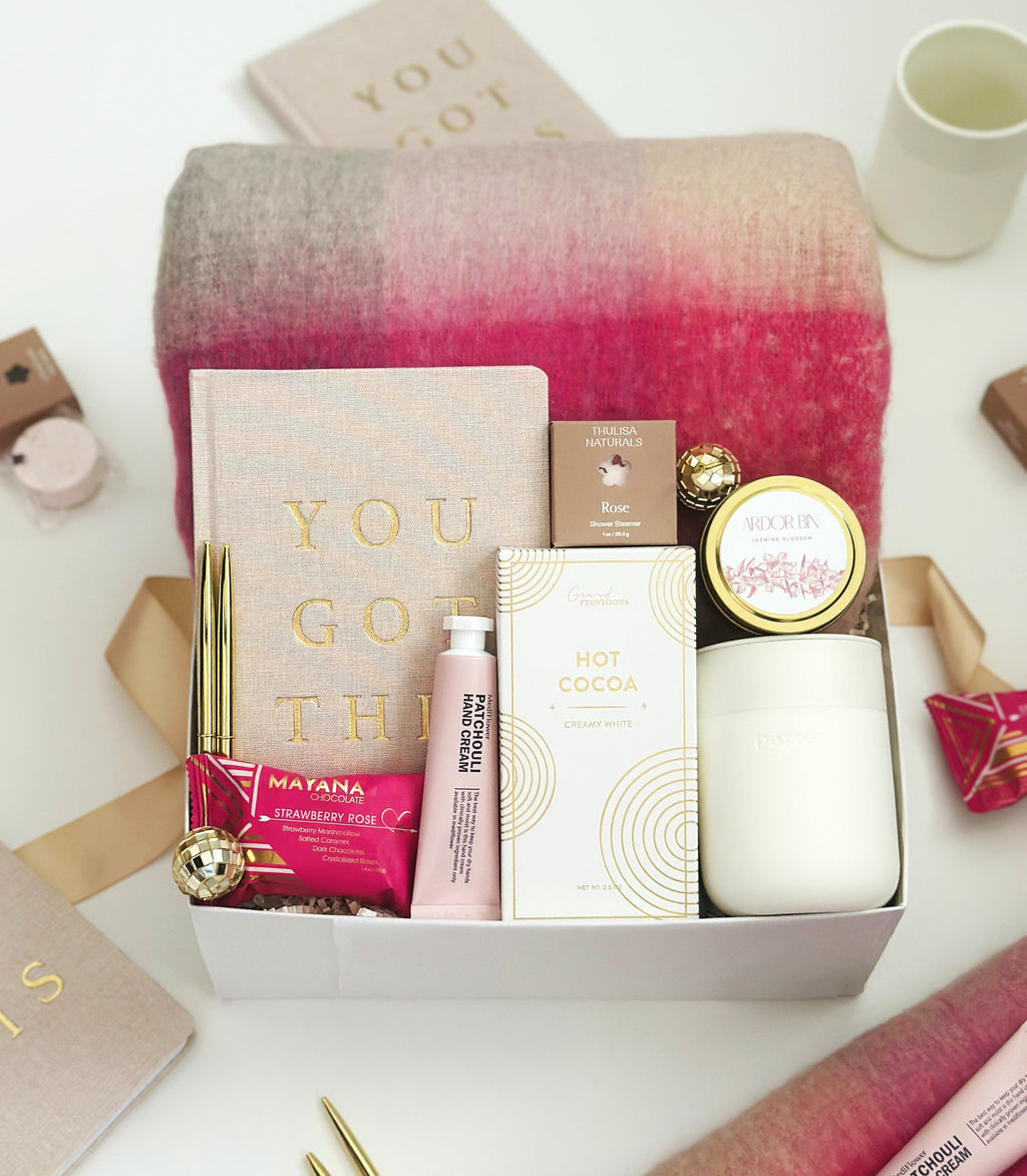 Gift box with holiday products and a blanket on a white surface